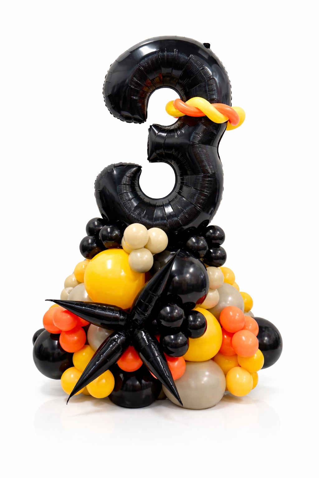 Black, yellow, and orange balloon sculpture shaped like the number '3' on a white background