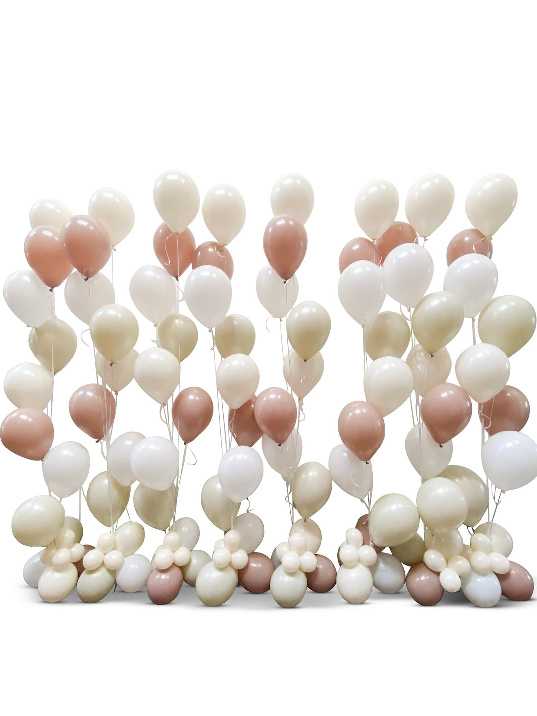 A wall of helium balloons in shades of white, rose gold, and silver, arranged to create a backdrop.