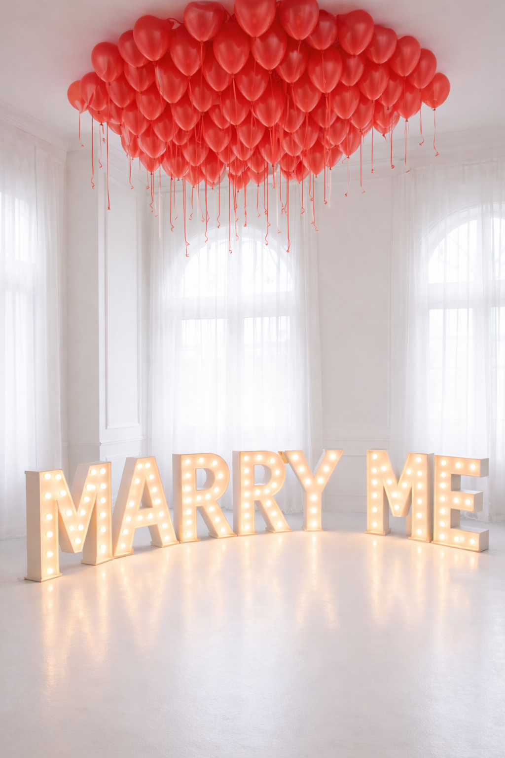 Red balloons and 'MARRY ME' sign in a room with white curtains