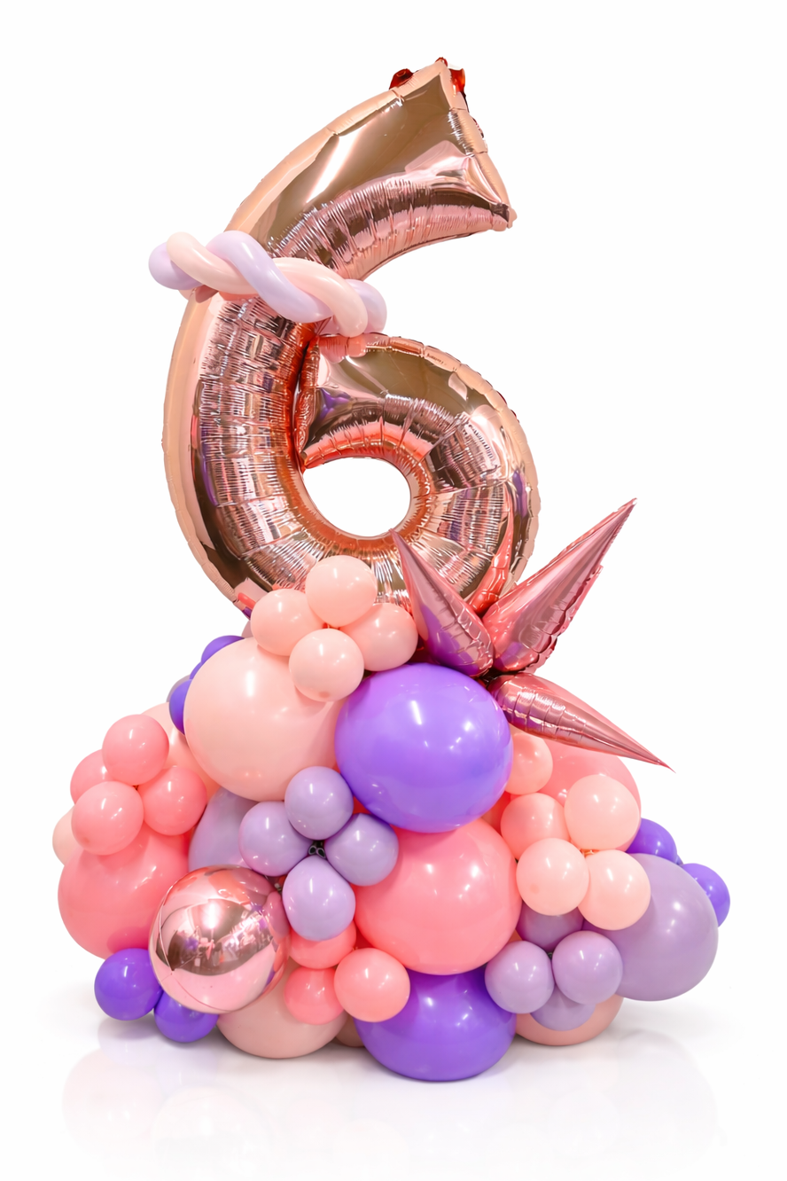 Balloon sculpture with a number 6 on top, featuring pink, purple, and gold balloons.